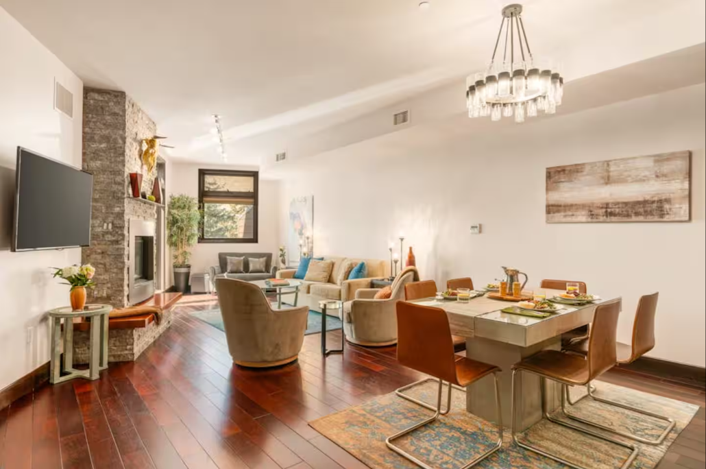 Open-plan living and dining room with stone fireplace and chandelier
